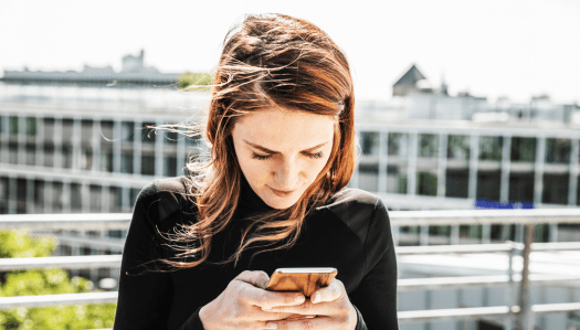 A woman is using her smartphone - happy with the user expierence of her new app.